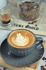 Cup of hot cappuccino coffee with beautiful latte art in a beautiful glass on the table