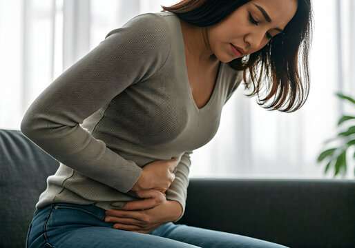 Woman experiencing abdominal pain discomfort at home suggesting health and wellness content for articles blogs or medical advertisements.
