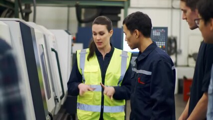 A female supervisor explains machinery operation to a team of workers in a manufacturing facility, promoting collaboration and training.