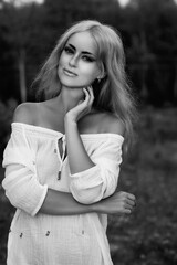 Obraz premium Portrait of a young beautiful blonde girl in light clothes outdoors in summer. Black and white photo.
