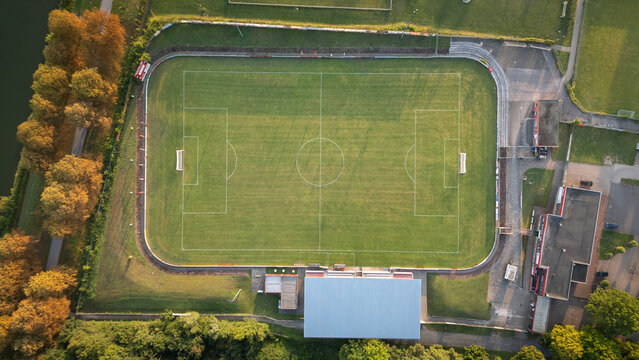 Aerial top-down view of a football field with green artificial turf and clear markings, sports infrastructure on a sunny summer day.