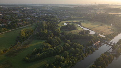 Drone aerial view of small lakes, meadows, and a rural village in Germany at golden hour.