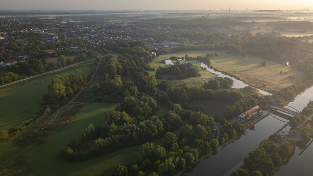 Drone aerial view of small lakes, meadows, and a rural village in Germany at golden hour.
