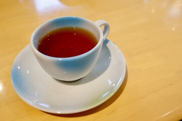 ほうじ茶の入った白いティーカップと木製テーブルの背景