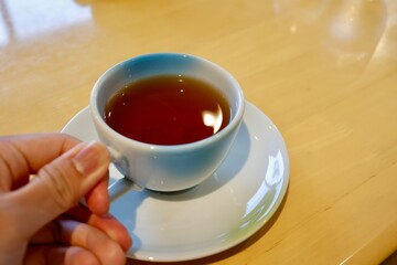 ほうじ茶の入った白いティーカップと木製テーブルの背景