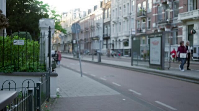 Blurry street scene with women walking along a european city sidewalk, showcasing defocused urban architecture and relaxed outdoor atmosphere under the soft bokeh light.