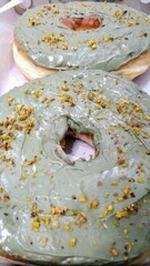Freshly baked green donuts with decorative sprinkles, ready to eat. Great for food-related content, dessert menus, or sweet indulgence themes.