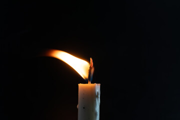 Warm candle flame burning brightly against a dark backdrop creating intimacy and peace for quiet...