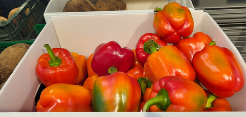 Red peppers in a white box on a store shelf.