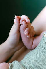 Mother’s hand holding newborn baby’s hand