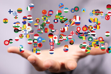 Image of many national flags floating above an open hand, representing global unity and international relations.