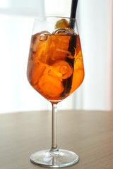 Aperol spritz cocktail with ice cubes and orange slice in a clear wine glass