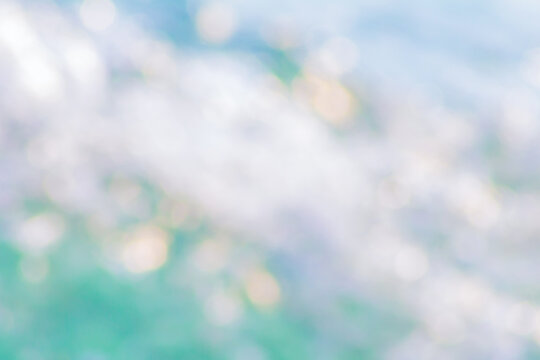 Sea water, sky, sun glare abstract blurred background. Natural bokeh lights on blue turquoise white summer background.