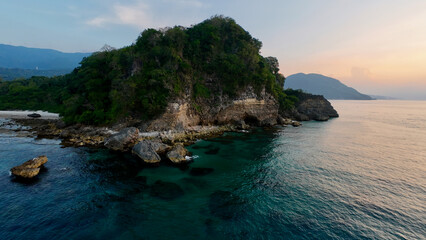Aerial view of rocky cliff at sunset. View from above of rocky coastline of tropical island during sunset.
