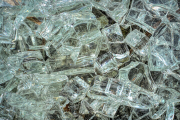 Pile of shattered glass, reflecting light and creating abstract patterns. Texture reveals sharp edges and transparency.