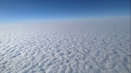 Vast white fluffy clouds spread across a bright blue sky from a top view perspective at high altitude