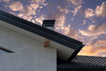 Gable eaves with soffit panel, metal roof tile and chimney © Sergey