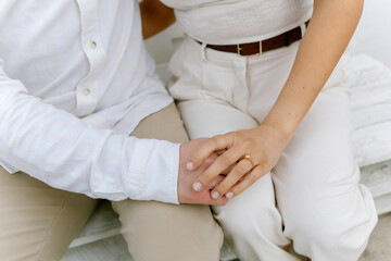 Couple holding hands with engagement ring in neutral tones