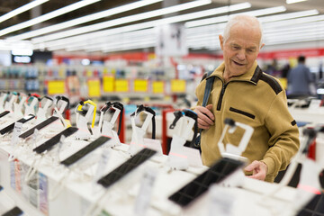 elderly man examines smart watch in showroom of electronics store