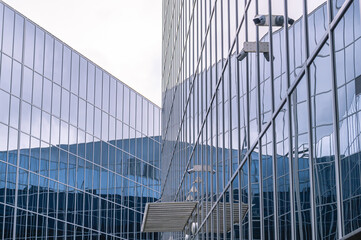 A building with a glass facade and video surveillance cameras for monitoring and security. Mirrored glass for building facades. Mirror-coated glass for facade glazing.