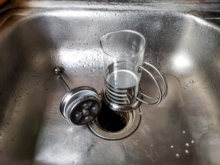 A dirty french coffee press in the sink.