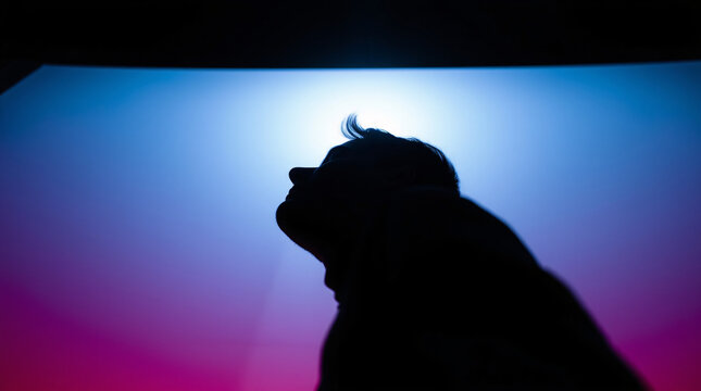 Silhouette of a person standing against a vibrant, colorful gradient background.