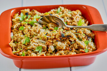 Thanksgiving stuffing with croutons, fresh herbs, and mixed nuts, with serving spoon