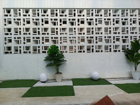 Modern exterior design featuring a geometric breeze block wall and a checkered lawn
