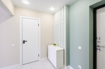 Minimalist entryway with white doors, a small dresser, and light-colored walls