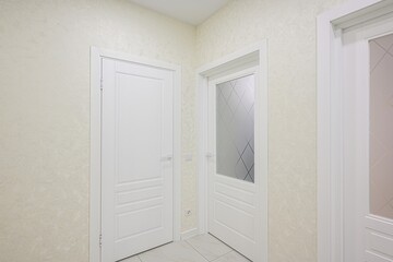 Bright room featuring white doors, textured walls, and light tile floor. Modern, clean, and minimalist interior design
