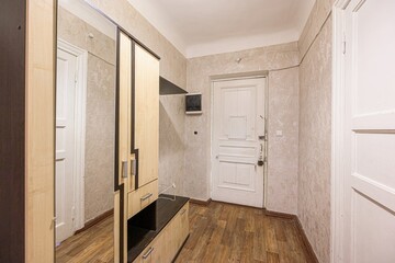 Hallway view with wooden flooring, wardrobe with a mirror, textured walls, and white doors