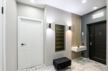 modern entryway featuring a white door, grey walls, a dark front door, and stylish details like a floating shelf, wooden slat accent, and marble-like flooring