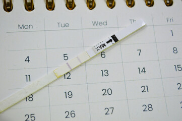 pregnancy test showing two stripes on white clean calendar . Calculation of ovulation day. Planning maternity. Gynecology and women's health concept. Top view
