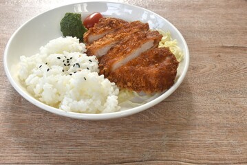 deep fried slice pork or tonkatsu with cabbage tomato and broccoli vegetable on black sesame rice in plate