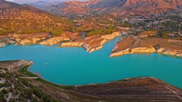 Drone video showing turquoise waters and rocky shoreline in Spain, with golden hour sunlight highlighting the rugged cliffs and surrounding landscape.