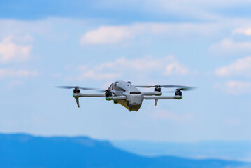 Drone flying over mountains under blue sky with clouds