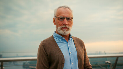 Woman and elderly man sit on park bench looking at smartphone
