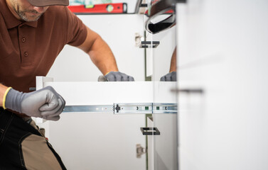Skilled Worker Assembling Kitchen Cabinet Drawers in Modern Kitchen