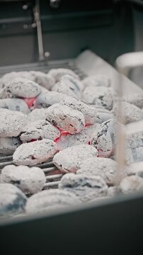 Close-up of white-hot charcoal briquettes with bright orange flames rising on a barbecue grill, ready for outdoor cooking.