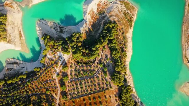 Drone video of the turquoise Guadalest Reservoir in Spain, surrounded by green hills and mountains, showing vivid water colors and scenic Mediterranean landscapes.