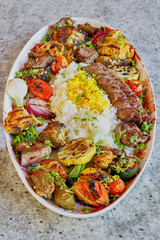 meat kebab with lamb, beef, pork, and chicken with mixed vegetables and yellow rice
