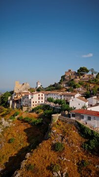 Drone video of the historic hilltop village of Guadalest in Spain, showcasing its ancient castle, charming houses, and surrounding mountains under clear blue skies.