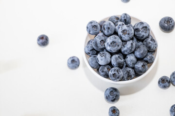 Blueberry is tasty, healthy and delicious fruits. Fresh blueberries heap in white bowl. Wild blueberries in plate with copy space for background.