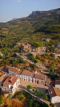 Drone video of the historic hilltop village of Guadalest in Spain, showcasing its ancient castle, charming houses, and surrounding mountains under clear blue skies.