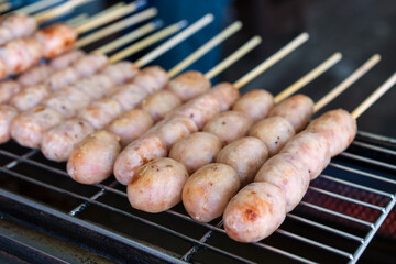 northeastern sausage on stick or skewered and arranged grilled burn on charcoal stove or hot isan sausage and barbecue meatball for traditional thai street food in local thailand or esan sausages