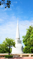 A beautiful white pagoda (stupa) surrounded by trees against a clear blue sky