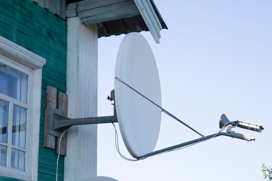 A TV satellite dish on the house wall.
