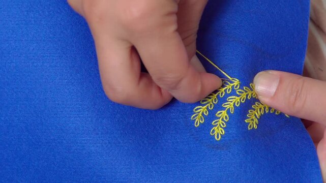 アクセサリーを手作りする女性の手元のクローズアローズアップ。葉っぱのモチーフを刺繍する様子。