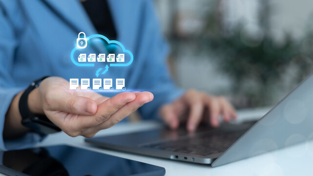 Businesswoman using laptop with secure cloud data storage icon and document transfer interface, concept of online backup, data protection, and cloud computing technology.