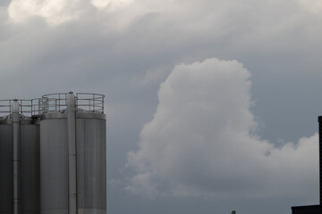 Two large industrial silos standing tall against a cloudy sky background